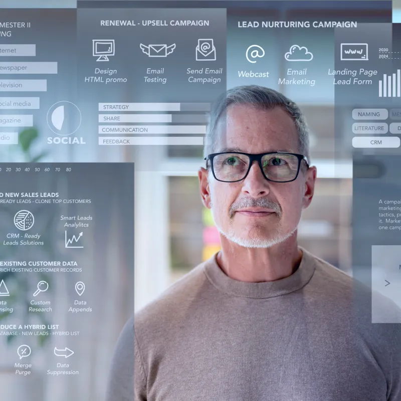 Middle-aged man with glasses looking sideways in front of a transparent screen displaying digital marketing and lead generation icons and charts.