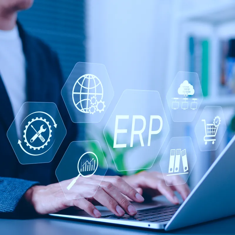 Person typing on laptop keyboard with translucent hexagonal icons showing ERP and related business process symbols.